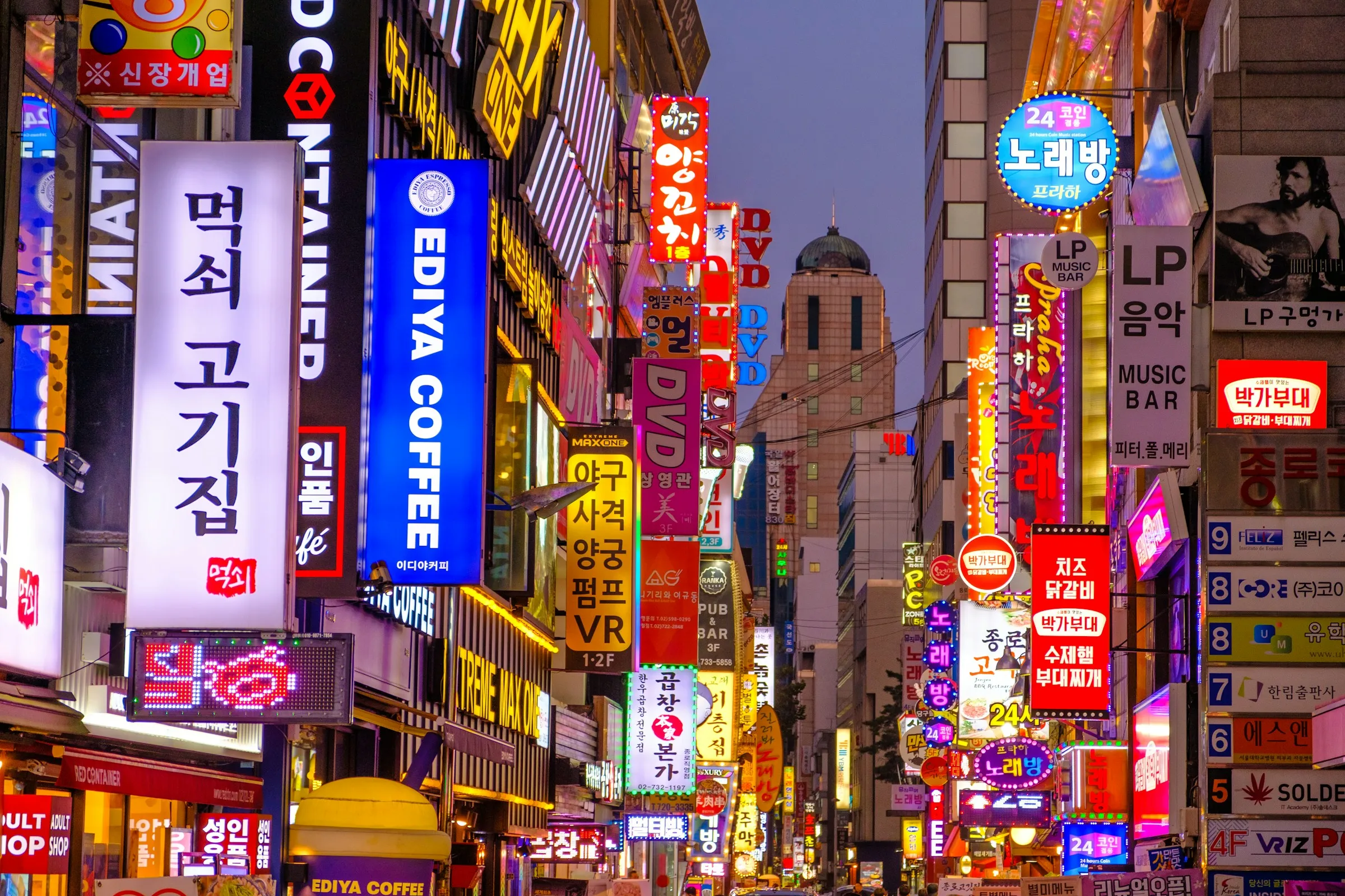 People walking through a neon-lit Seoul street at night